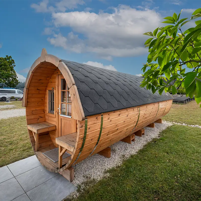 Außenansicht eines runden Campingfasses aus Holz auf einer grünen Wiese.