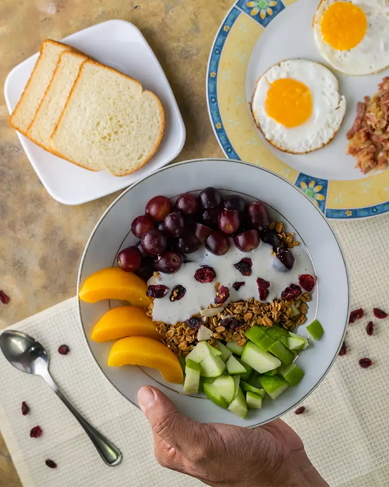 Reichhaltiges Frühstückstablett mit Müsli, Obst und Spiegelei im Hotel Reich.